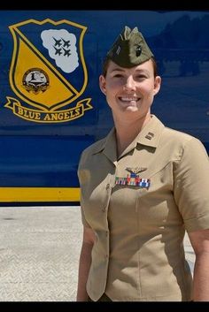 a woman in uniform standing next to a blue bus