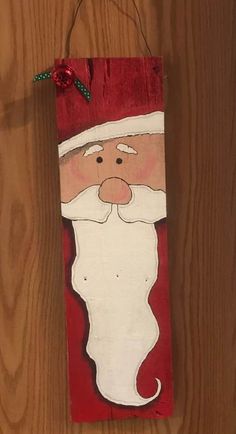 a wooden sign with a santa clause painted on it's face and red background