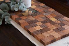 a wooden cutting board sitting on top of a table next to a vase with flowers