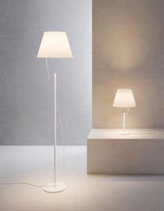 a lamp that is on top of a table next to a light fixture with a white shade