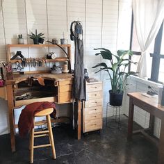 a room with a desk, chair and potted plant on the wall next to it