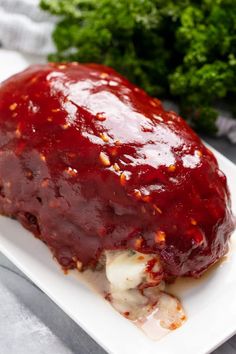 meatloaf covered in sauce and garnished with parsley on a white plate