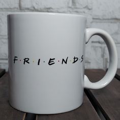 a white coffee mug with the word friends printed on it sitting on a wooden table