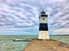 a light house sitting on top of a wooden pier next to the ocean under a cloudy sky