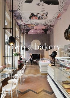 the interior of a bakery with lots of counter space and white chairs in front of it