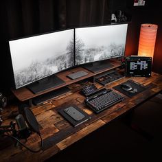 two computer monitors sitting on top of a wooden desk next to a keyboard and mouse