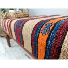 a multicolored bench sitting on top of a wooden floor next to a basket