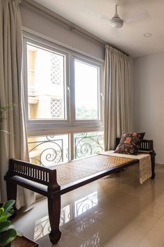 a bed sitting in the middle of a room next to a window with curtains on it