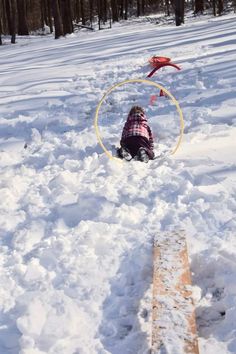 a child playing in the snow with a hula hoop