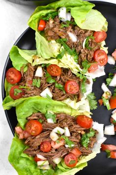 three lettuce wraps filled with shredded beef and tomatoes on a black platter