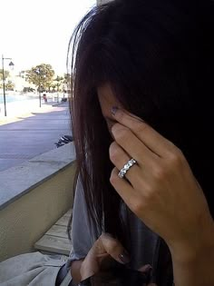 a woman holding her hand to her face while looking out the window at the street