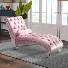 a pink chaise lounge chair sitting on top of a rug