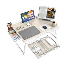 a computer desk with an open book, laptop and other items on top of it