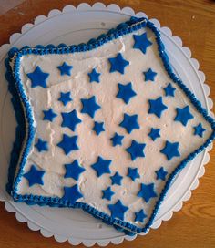 a blue and white cake with stars on it is sitting on a plate in front of a wooden table