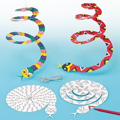 the paper snake is next to some scissors and other crafting supplies on a blue background