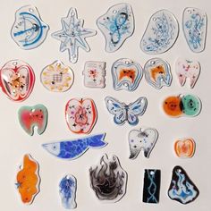 many different shapes and sizes of glass magnets on a white surface with blue, red, orange, and black designs