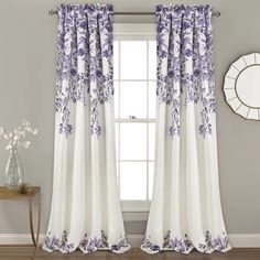 purple and white curtains hanging in front of a window with a mirror on the wall