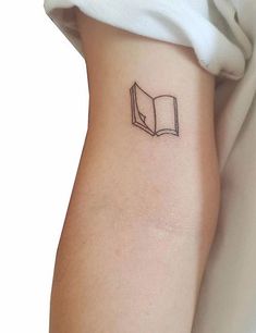 a small book tattoo on the left side of the arm is shown in black ink