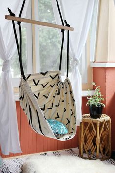 a hammock chair hanging from the ceiling in a room with white drapes