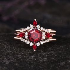 a close up view of a ring with red stones and diamonds on it, sitting on a black surface