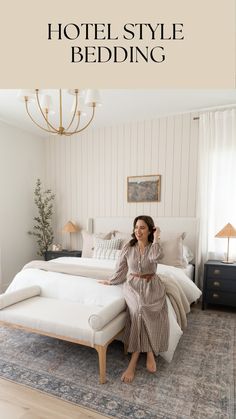 a woman sitting on top of a bed next to a white headboard and foot board