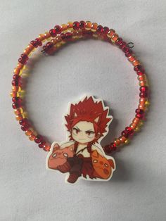 a bracelet with an anime character on it and some beads around the wrist, as well as a charm