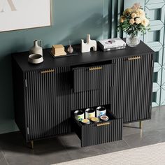 a black sideboard with drawers and vases on it