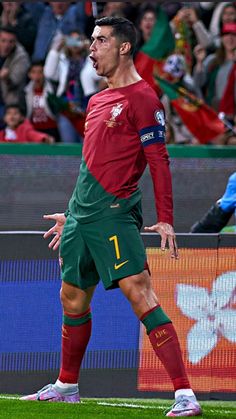 a soccer player in action on the field with people watching from the stands behind him