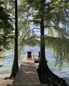 there is a dock that leads to the water and two chairs are sitting on it