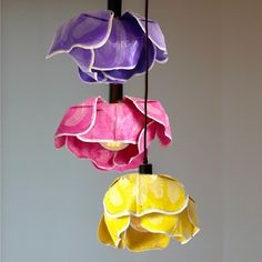 three different colored paper flowers hanging from a ceiling fixture in the shape of umbrellas