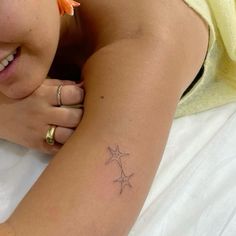 a woman laying on top of a bed with a star tattoo on her arm