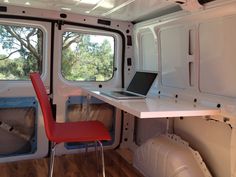 a laptop computer sitting on top of a desk in the back of a truck with windows