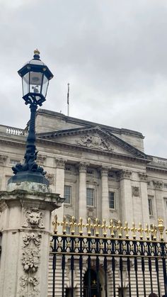 a large white building with a black iron fence and light pole in front of it