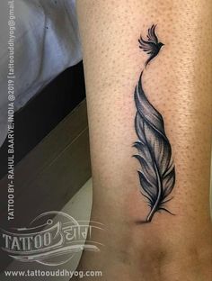 a black and white tattoo with a feather on the side of a woman's leg