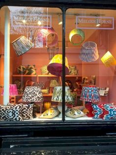 a store window with many lamps and pillows in the display case, including one that is brightly colored