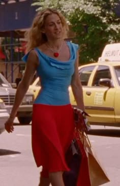 a woman is walking down the street with shopping bags in her hand and wearing a blue top