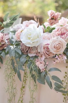 a bunch of flowers that are in some kind of vase on a table with greenery