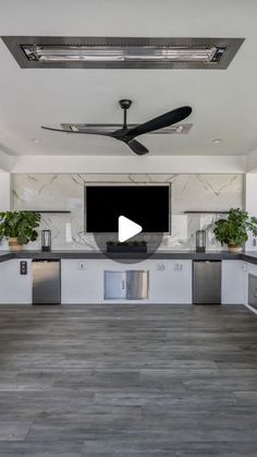 an empty kitchen with a ceiling fan and television on the wall in front of it