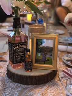 a table topped with a vase filled with flowers next to a bottle of jack daniels