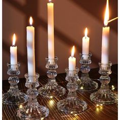 a group of candles sitting on top of a wooden table next to glass vases