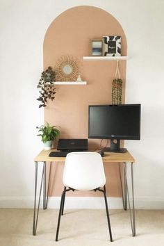 a desk with a computer on top of it next to a plant and potted plants