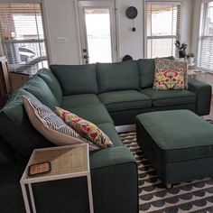 a living room with green couches and pillows on top of the sofa is shown