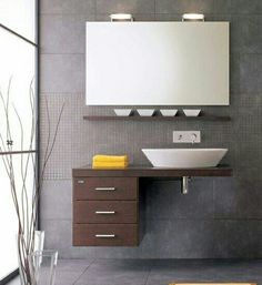 a bathroom with a sink, mirror and vase on the counter in front of it