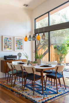 the dining room table is surrounded by modern chairs and rugs that match the hardwood flooring