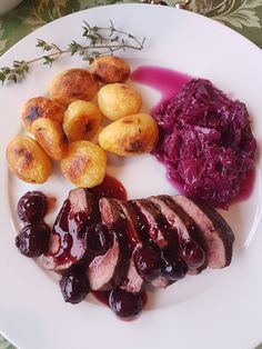 a white plate topped with meat, potatoes and cranberry sauce next to other foods