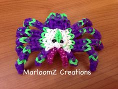 a purple and green spider brooch sitting on top of a wooden table with the words marloomz creations written below it