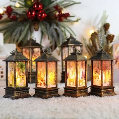 four lit up lanterns sitting on top of a white rug next to a christmas tree