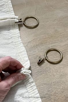 someone is holding onto the end of a pair of metal rings on a white towel