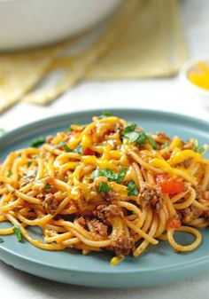 a blue plate topped with spaghetti and meat