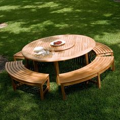 a picnic table with two benches and a plate of food on it in the grass